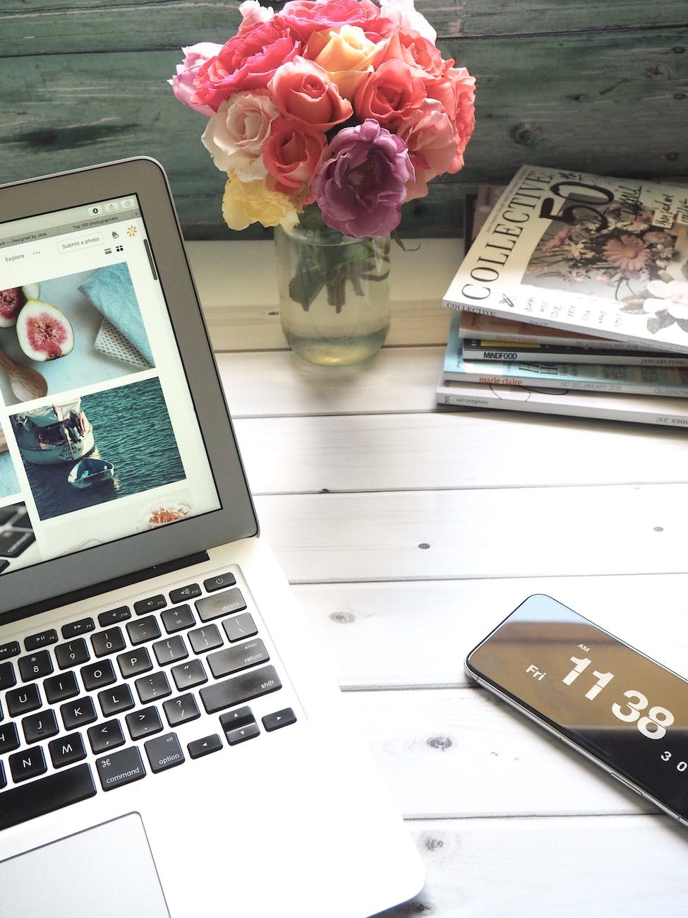 macbook air flower bouquet and magazines on white table